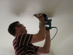 Cutting speaker holes in ceiling.